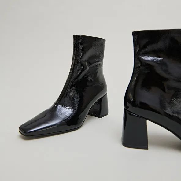 Pointed-toe ankle boots in black pleated patent